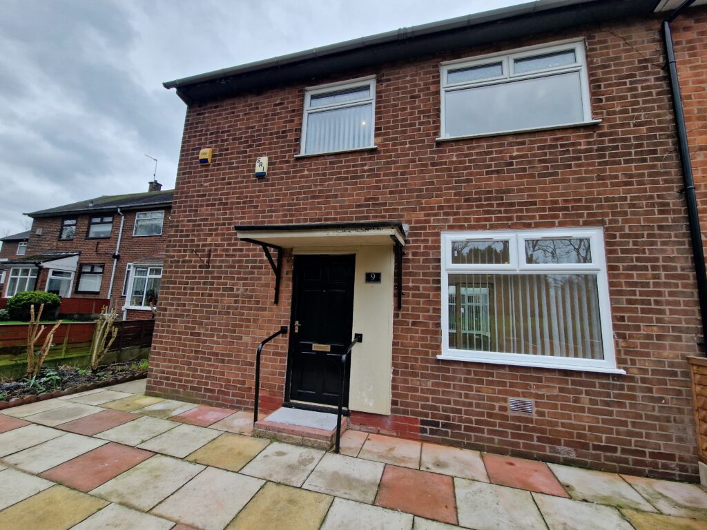 A brick house with a black door and white window.