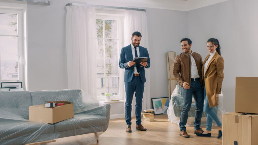 Two men in suits standing next to a couch.