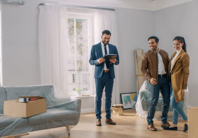 Two men in suits standing next to a couch.